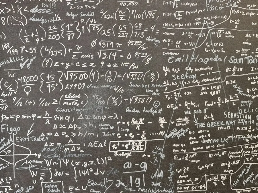Pizarra llena de fórmulas y ecuaciones matemáticas escritas con tiza